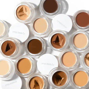 Many small glass pan sof RMS Beauty UnCoverup Concealer with a white cap that says "RMS Beauty,"