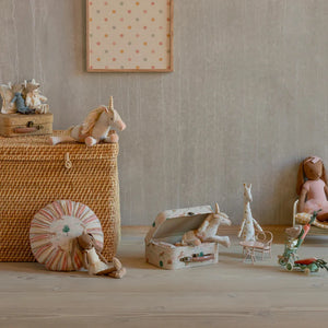 Children's toys including a doll, wagon, and small furniture on a wooden floor.