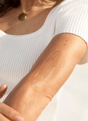 Close-up of a person's arm with a light brown color, wearing a white ribbed top.