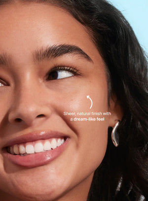 Close-up of a woman's face with text indicating a sheer, natural finish with a dream-like feel.