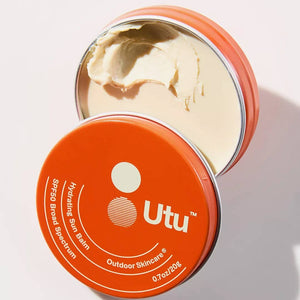 Open orange tin of Utu sun balm with visible cream on a white background