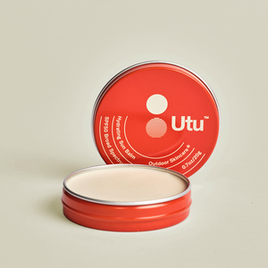 Red tin of Utu outdoor skincare balm on a beige background