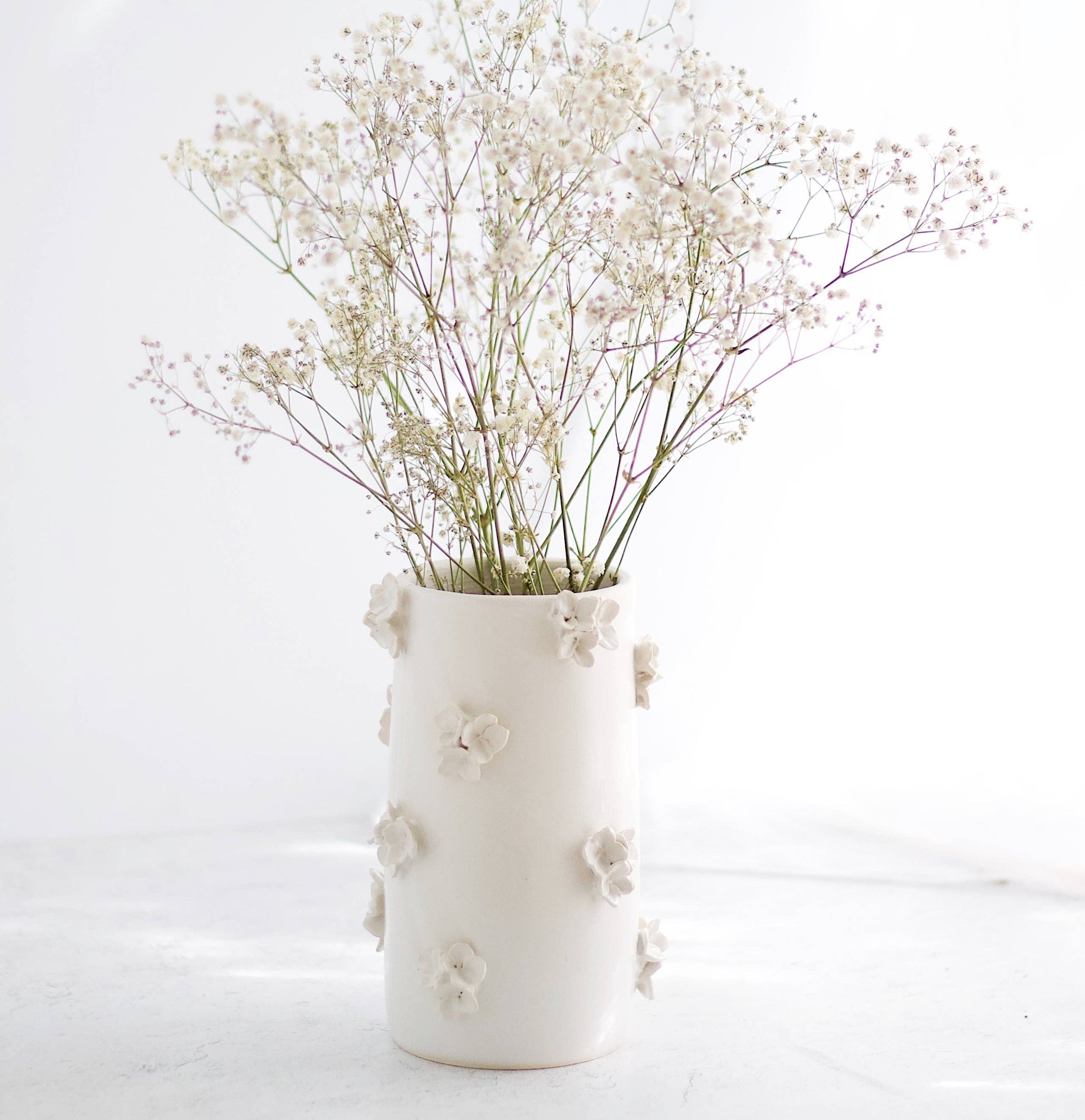 A white ceramic vase holding flowers. 