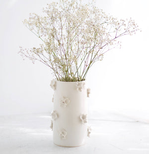 A white ceramic vase holding flowers. 