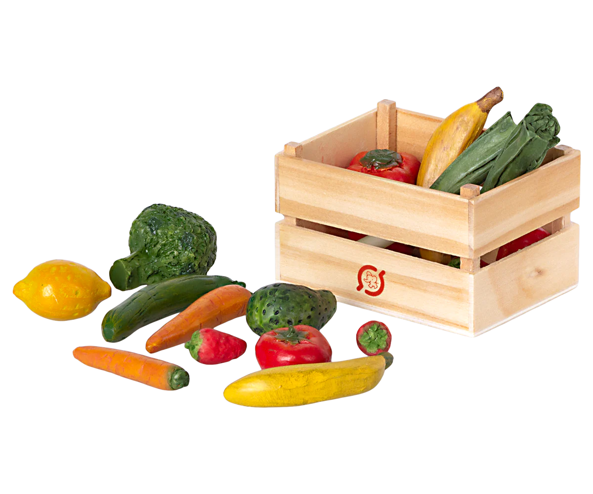 A wooden crate filled with miniature play fruits and vegetables, including carrots, cucumbers, and tomatoes.