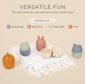 Assorted bath toys on a white towel with the words "Versatile fun, mix and match the tops for creative play."
