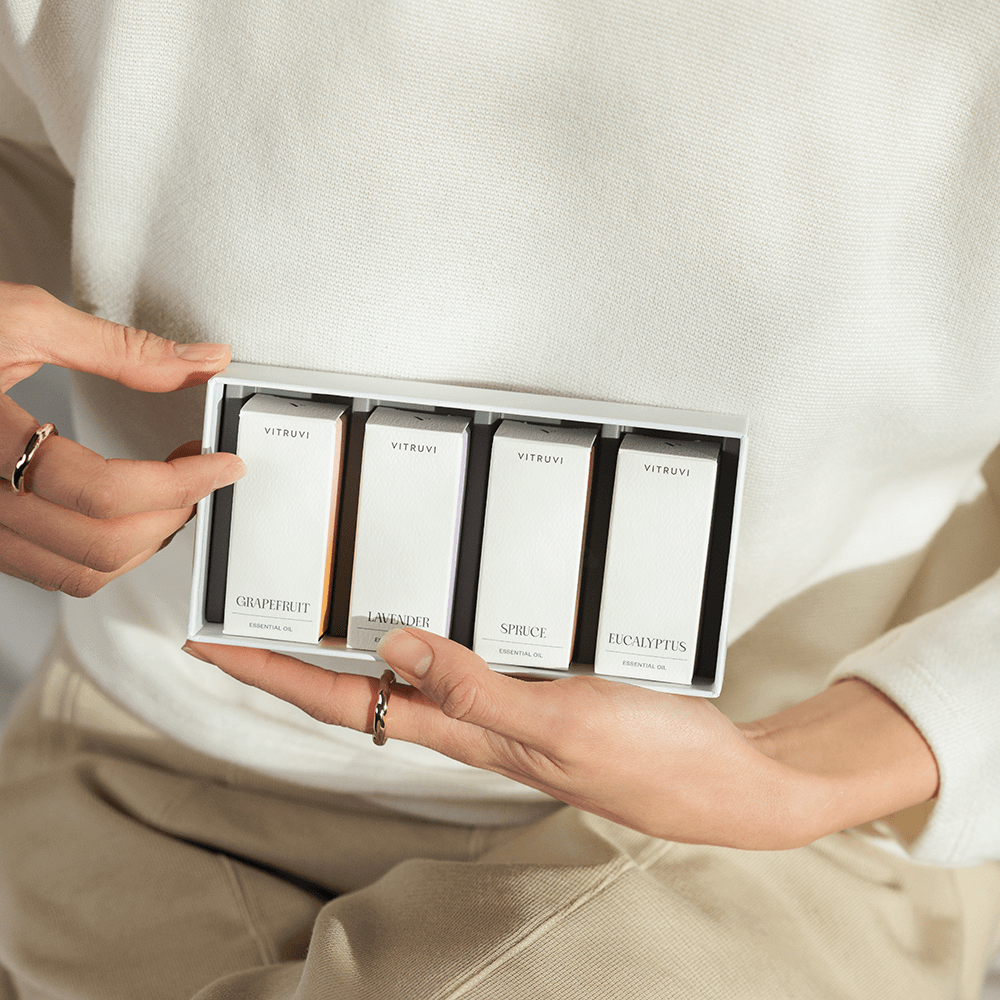 Person holding a set of Vitruvi fragrance sample boxes.