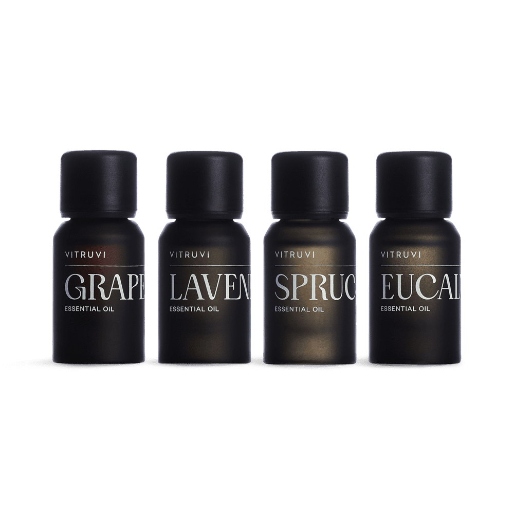 Four VITRUVI essential oil bottles on a green background