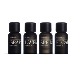Four VITRUVI essential oil bottles on a green background