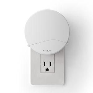 White plug in diffuser attached to a wall outlet with 'Vitruvi' branding on a white background