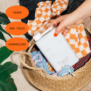 A laundry basket with laundry and a container of Dedcool laundry detergent. The words Vegan, Non-toxic, and Genderless appear. 