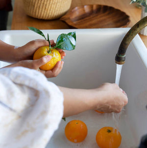 A sink full of oranges that are being washed. 