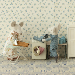 Two mice in a playful setting with floral wallpaper and vintage furniture.