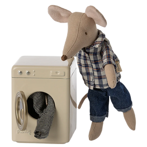 Stuffed mouse toy in plaid shirt and jeans next to a washing machine.