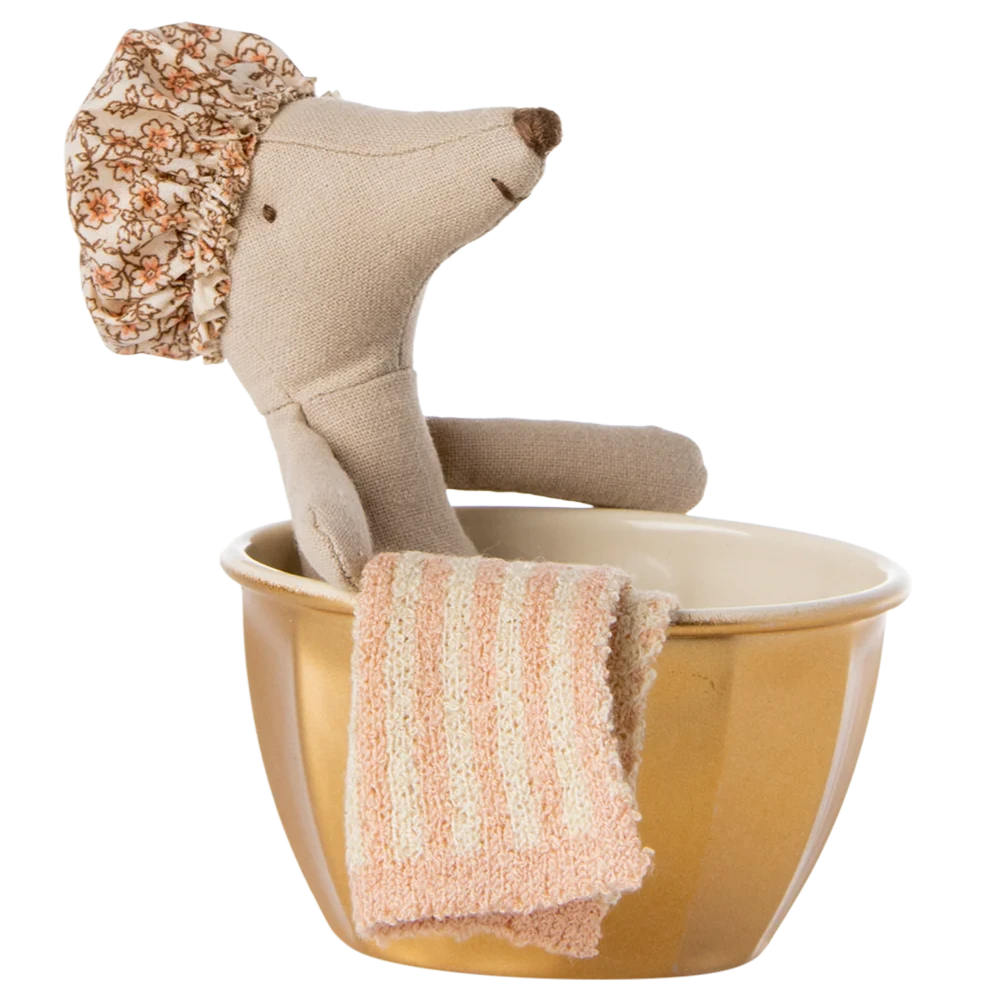 A toy mouse with a shower cap on its head sitting in a golden metal bathtub with a pink towel.