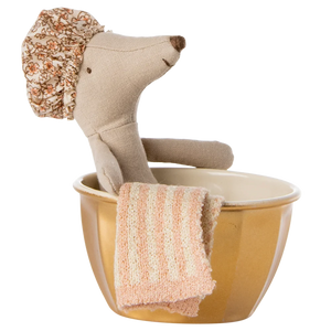 A toy mouse with a shower cap on its head sitting in a golden metal bathtub with a pink towel.