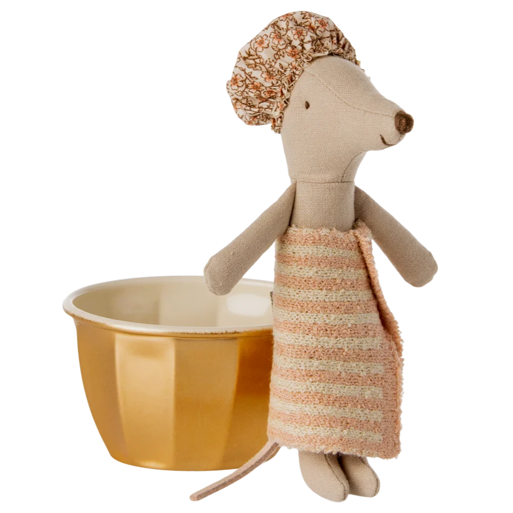 A toy mouse with a shower cap on its head sitting in a golden metal bathtub with a pink towel.