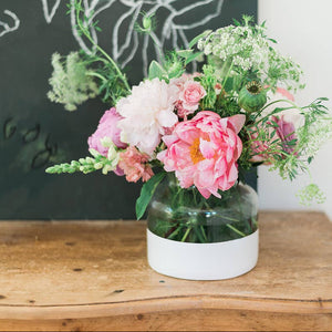 A white color block vase with flowers on a table.
