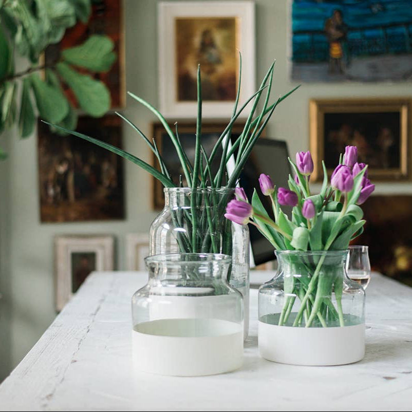 A group of white color block vases on a table with art in the background. 