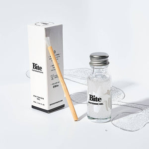 A bottle of Bite whitening gel, a bamboo applicator brush, and a white box on a white background. 