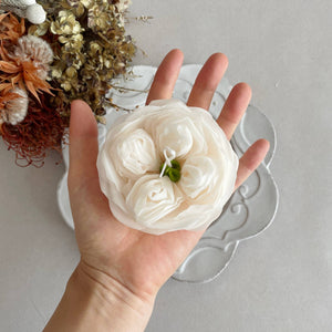 Hand holding a white floral arrangement against a neutral background