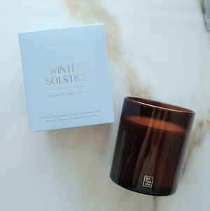 Brown candle and 'Winter Solstice' box on a marble surface