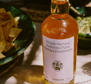 A bottle of winter harvest persimmon vinegar with plates of food. 