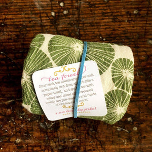 A green and beige tea towel on a wood texture surface. 