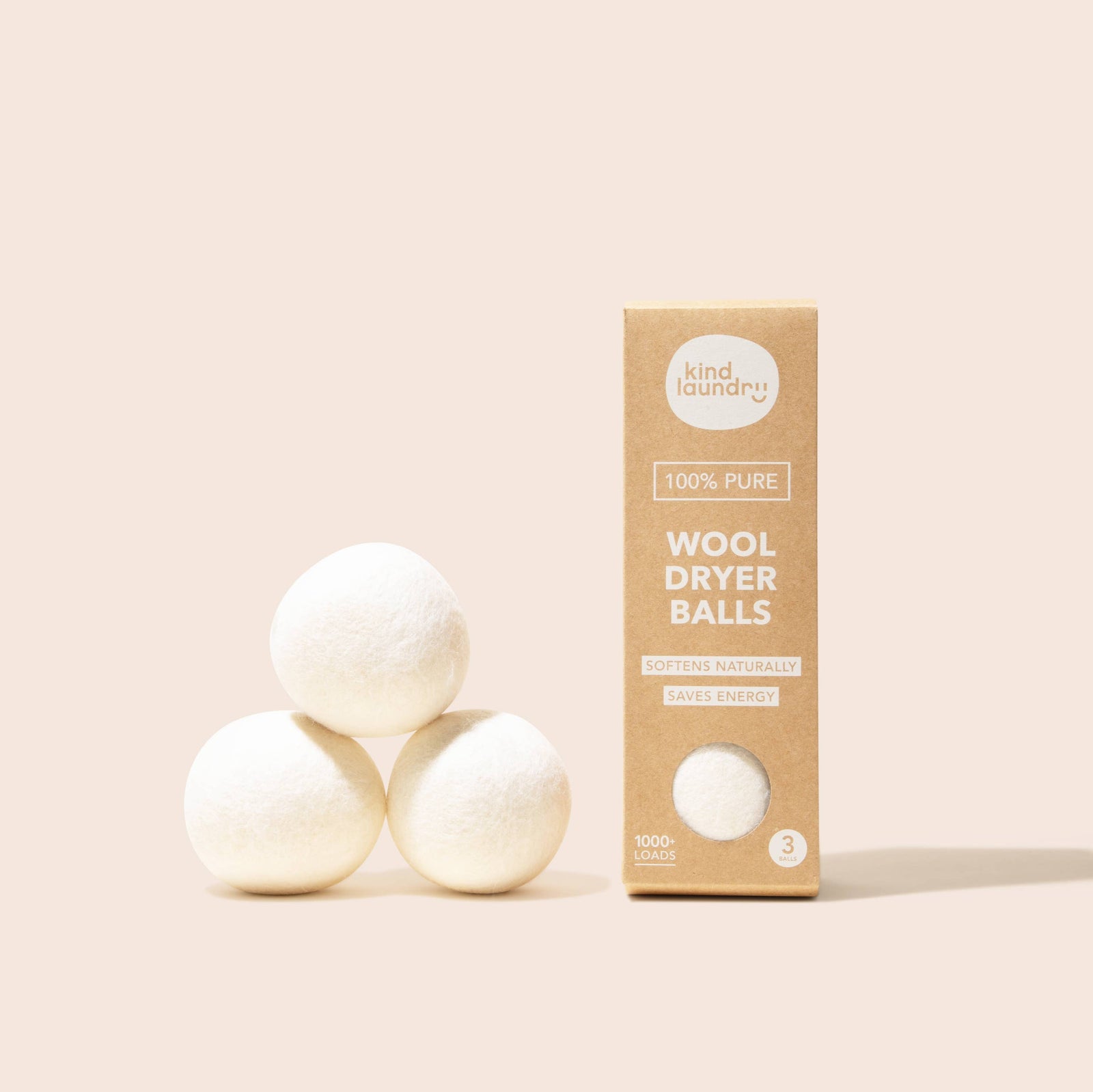 Three white wool dryer balls next to a beige package labeled 'Wool Dryer Balls' by Kind Laundry.