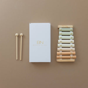 A colorful pastel Brooklyn neutral xylophone and white box on a beige background.