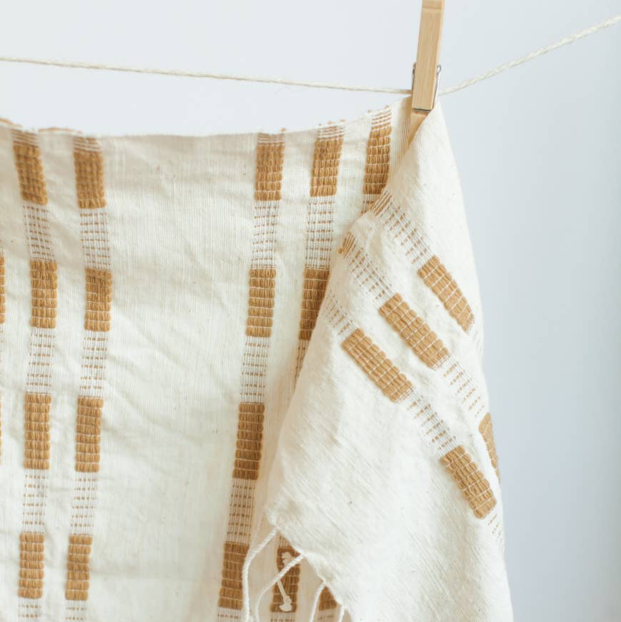 A yellow and white tea towel with a clothespin.
